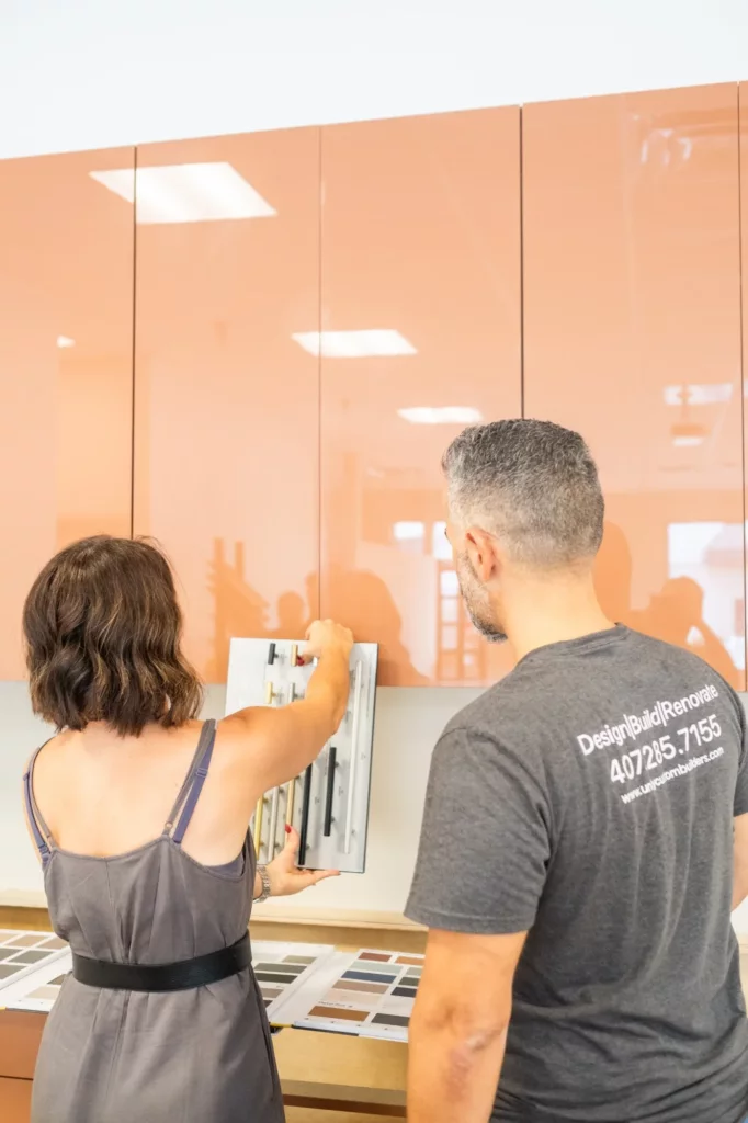 Designer comparing cabinet pull samples against high-gloss upper doors with a Unity Cabinetry team member