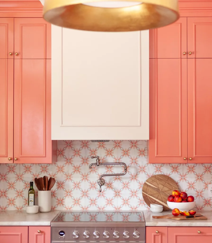 Coral shaker cabinetry around a range with patterned tile