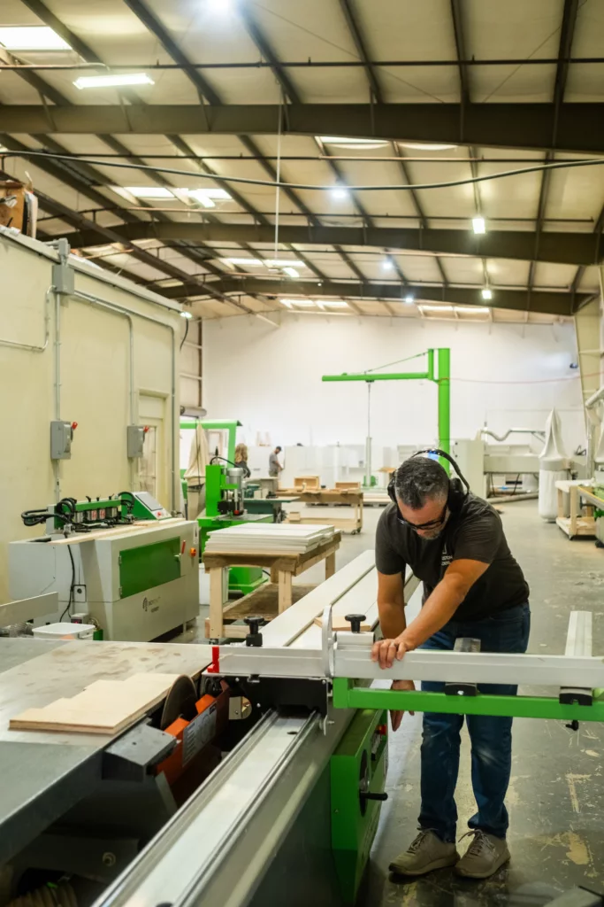 Craftsman guiding a panel through the beam saw on the workshop floor